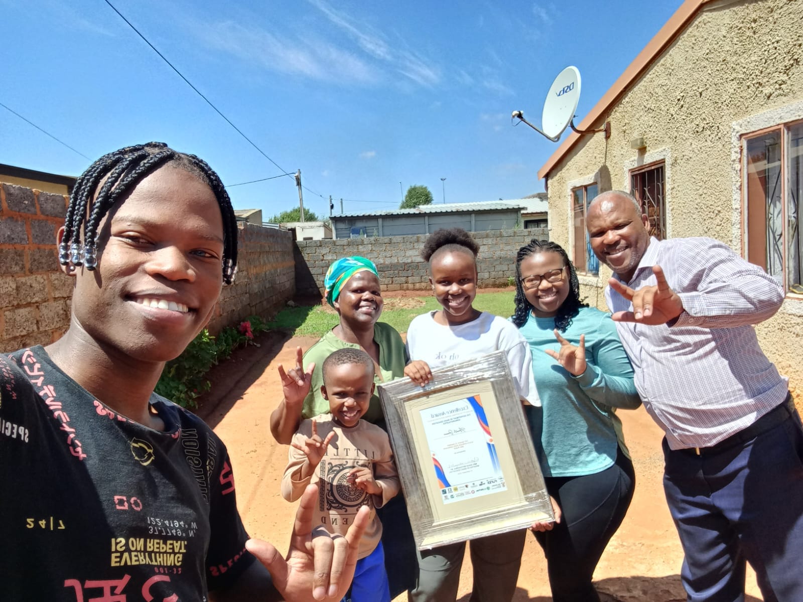Amahle Jemane holding her matric award, alongside are her parents and siblings celebrating her achievement.